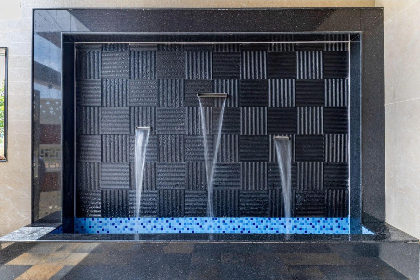 Courtyard water feature with a textured black stone wall