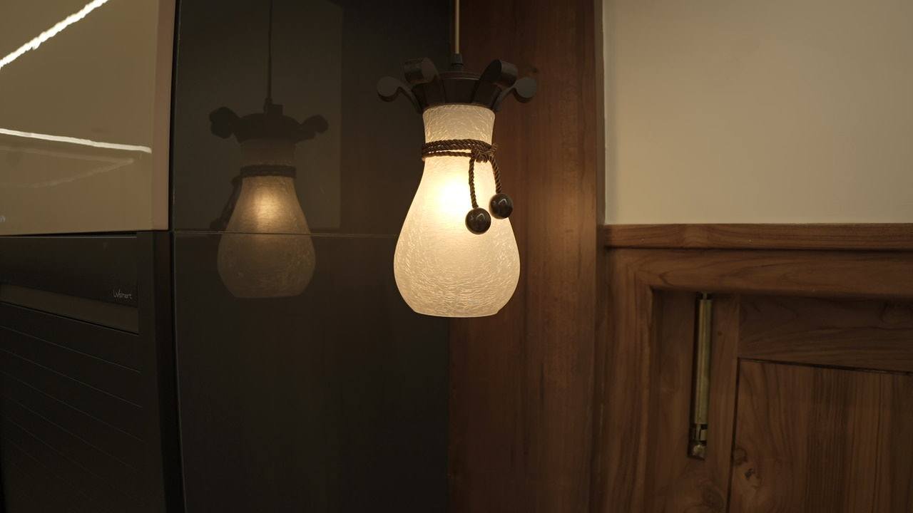 Pair of frosted pendant lamps beside timber panelling