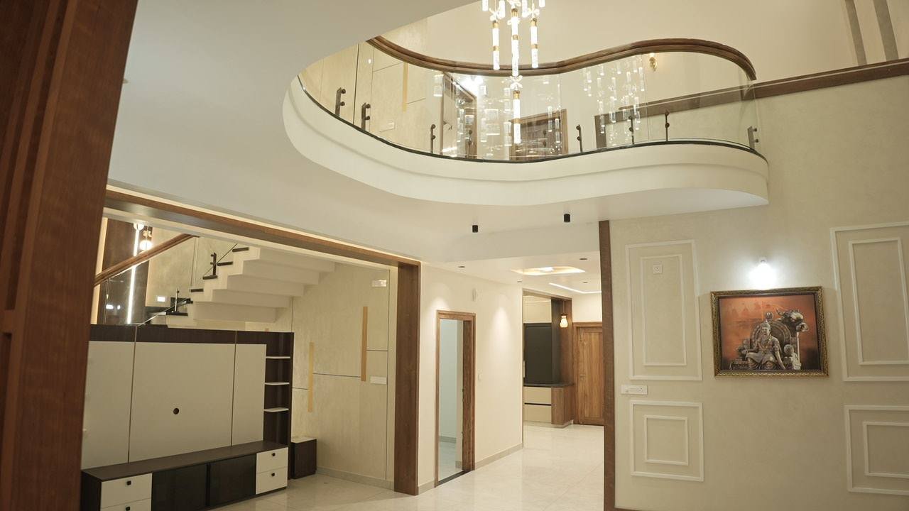 Double-height living room with a curved balcony above and moulded wall panels