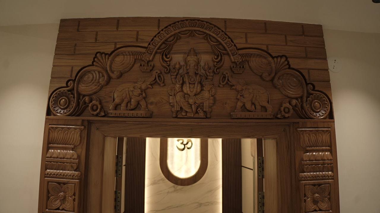 Hand-carved Ganesha doorway framing the glowing pooja arch